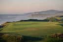 Golf course with ocean and mountains in the background
