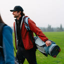 Man in Monsoon Hooded Jacket carrying a golf bag