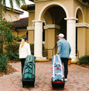 A woman and a man pulling ClubGlider3 travel bags into a golf club
