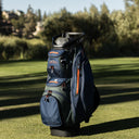 Golf bag on a grassy field with trees in the background