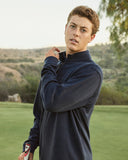 Person wearing a dark blue pullover on a golf course with trees in the background