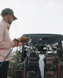 Person cleaning golf clubs with a brush in front of a golf cart