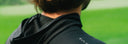 Close-up back view of a person wearing a black hooded athletic top outdoors