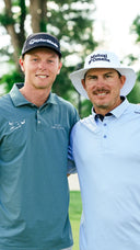 Ryggs Johnston (left) and Joel Dahmen (right) standing together on a golf course before a match. 