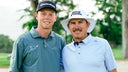 Ryggs Johnston (left) and Joel Dahmen (right) standing together on a golf course before a match. 