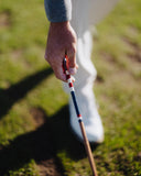 Person holding an alignment stick on a grassy field