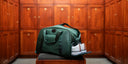 Matchplay Ballistic duffel with shoes in grove staged in a locker room 