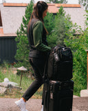 Woman walking with the Matchplay Ballistic Carry-on and Backpack in black