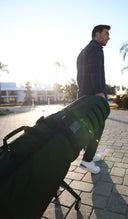 Man walking with a green ClubGlider Meridian on wheels outdoors