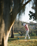 Person playing golf on a grassy field with in the Coastal Hoodie