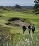 Three golfers walking on a golf course with a scenic background