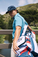 Person holding a golf bag with a scenic background
