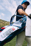 Person holding a golf bag with USA branding on a golf course