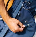 Person opening a blue Matchplay Ballistic golf bag with a visible brand logo.