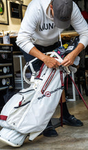 Close-up of a person with white golf bag with red and black Sun Mountain and MUNICIPAL branding